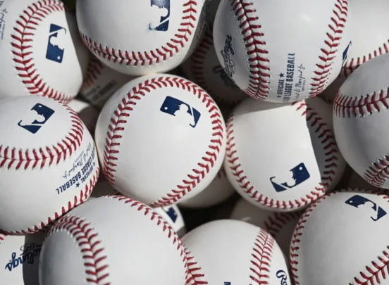 A pile of official Major League Baseballs with red stitching and MLB logos stacked closely together.
